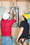 Electrician and apprentice changing out a faulty circuit breaker in an industrial panel.