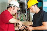 Electrician and apprentice repairing a circuit breaker from an industrial panel.