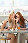 Two girls sit in cafe and smile, showing forward
