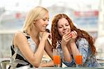 Two young women in a cafe show a manicure one other