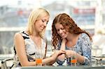 One girl shows other the ring in a cafe, horizontally