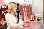 The blonde with packages in an underwear boutique holds a credit card in a hand