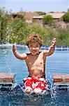 Cute young boy splashing in a swimming pool