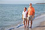 Happy senior couple enjoys a romantic stroll on the beach.