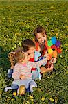 Woman and kids playing with a windmill toy on the spring flower field