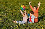 Spring sun worshipers - woman with kids on the flower field having fun
