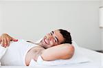 Handsome man lying in his bed smiling