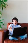 Kid using his laptop at home with thumb up