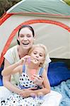 Mother and daughter having fun with bubbles in tent
