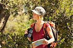 young blonde woman hiking and holding binoculars and map.