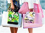Two young girl friends holding shopping bags at mall