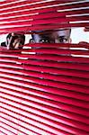 afro-american businessman glancing through red blinds. Copy space