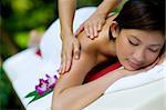 A young woman having massage outside in tropical garden