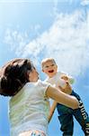 Mother throwing baby against blue sky