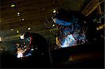 Two factory welders welding a parts in a factory