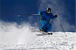 Skier jumping on a slope against blue sky.