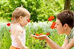 Mother showing poppy flower to her daughter
