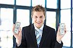 Smiling businessman holding dollars in office