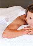 Isolated young man relaxing in bed looking at the camera