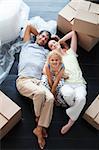 Parents and daughter on the floor of their new house with a lot of boxes