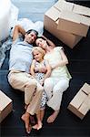 Parents and daughter lying on the floor of their new house