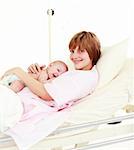 Patient with newborn baby in hospital smiling at the camera