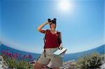 young blonde woman hiking watching through binoculars. Copy space