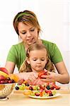 Woman and little girl slicing fruits preparing a healthy snack