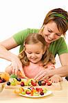 Happy woman and little girl slicing fruits for a healthy salad