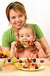 Woman and little girl eating fruit slices on a stick - healthy snack