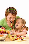 Woman and little girl eating fruit slices on a stick