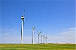 Wind turbines farm in green field over cloudy sky