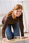 Attractive young redhead woman cleaning up a water spill in her home. Vertically framed photo.