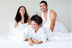 Happy family playing with his son in bed