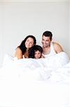 Happy family playing with his son in bed with copy-space