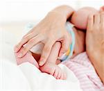 Patient's hands holding a newborn baby in bed in hospital