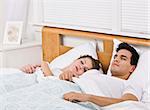 An attractive young couple sleeping in bed together.  They look peaceful.  Horizontally framed shot.