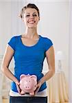 Beautiful woman holding piggy bank. Vertically framed shot.