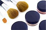 A set of three make-up brushes and four jars with mineral powder foundation.  Isolated on white background, with shadow.