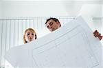 two architects examining blueprint indoors. Low angle view. Copy space