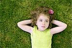 Beautiful little toddler girl happy lying on the green grass