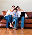 Young family using a labtop on sofa in living-room