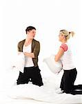 Happy young boy and girl having a pillow fight