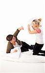 Happy young couple having a pillow fight