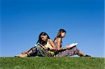 Two young girls reading isolated on blue sky