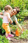 Baby girl helping mother in the garden