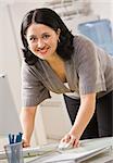Une femme d'affaires est debout sur un ordinateur et souriant à la caméra. Photo encadrée verticalement.