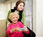 Teen girl teaching her grandmother how to play video games.  Fun family moment.