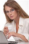 La jeune femme moderne en points, est assis à une table, avec l'ordinateur personnel, tient une tasse de café et l'air dans la chambre