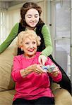Teen girl helping her grandmother learn how to play a video game.